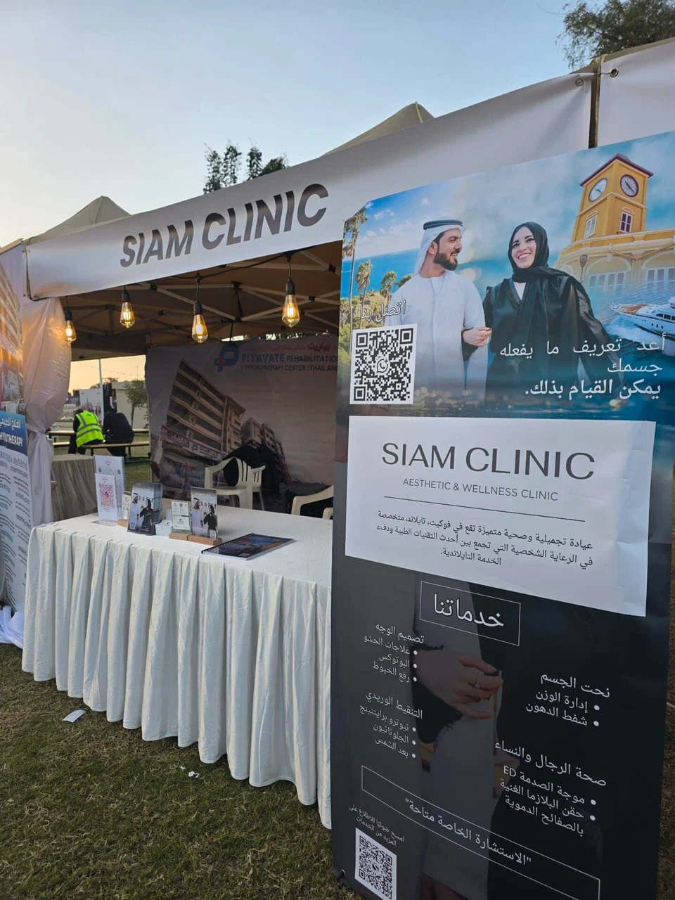 Siam Clinic booth at the Thai Festival in Muscat, Oman, with a large banner and promotional material.