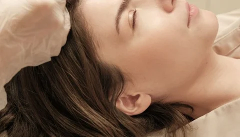 A woman receiving a facial injection treatment while lying down with her eyes closed.