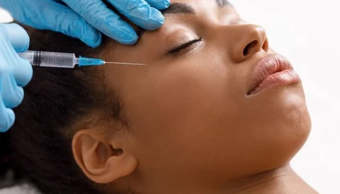 Woman receiving facial injection treatment in a clinic setting.