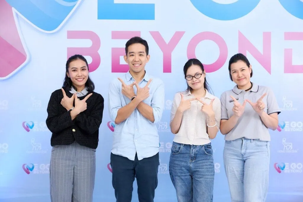 A woman, a man, and two women standing together at an event, smiling and making a gesture with their.