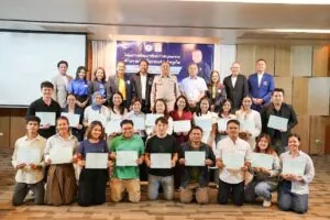 Group of people on stage holding certificates at a training event.