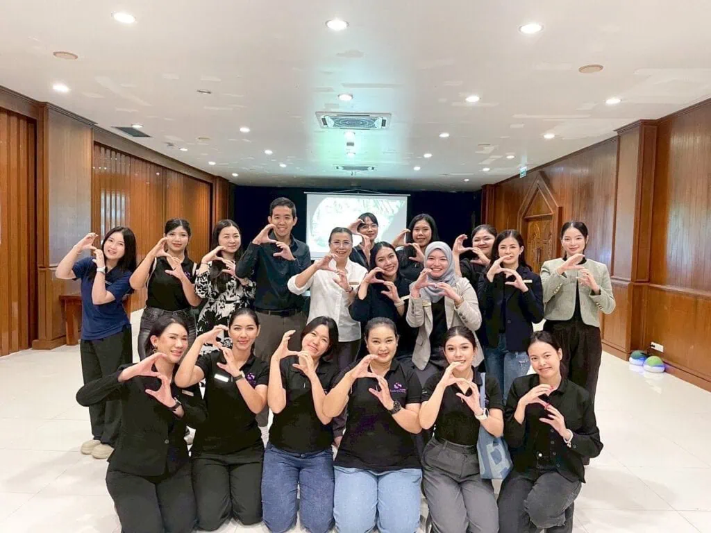 A group of people posing together indoors, some making heart shapes with their hands.