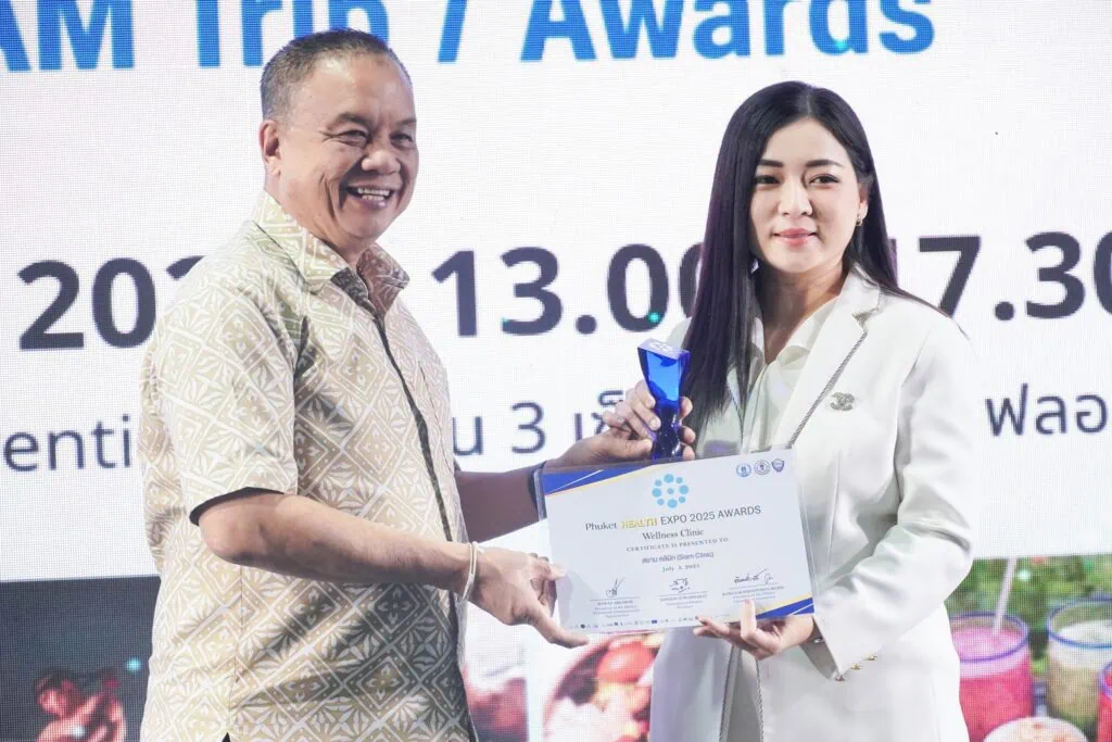 A woman receiving an award from a man on stage at the Phuket Health Expo 2025.