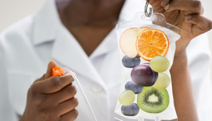 Fresh fruit slices in a clear IV bag, held by a person in a white coat.