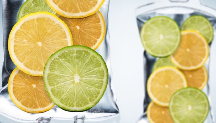 Fresh lemon and lime slices in a glass pitcher and a glass container.