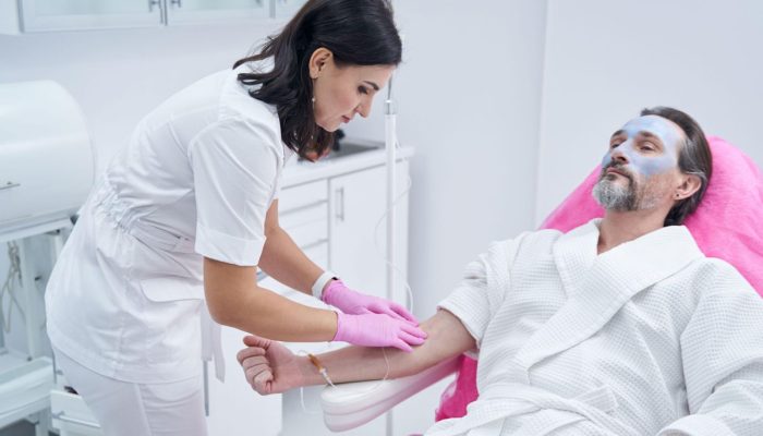 An intravenous therapy session with a nurse administering fluids to a patient lying on a bed.