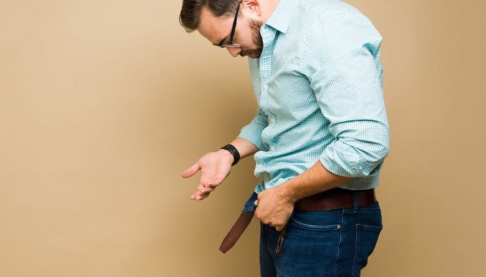 A man looking at his empty pocket, indicating concern about finances or health.