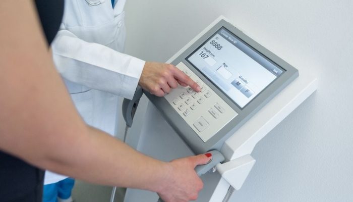 Medical professional operating a body composition analysis device in a clinic setting.